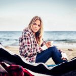 Portret młodej kobiety pijącej przez namiot na plaży