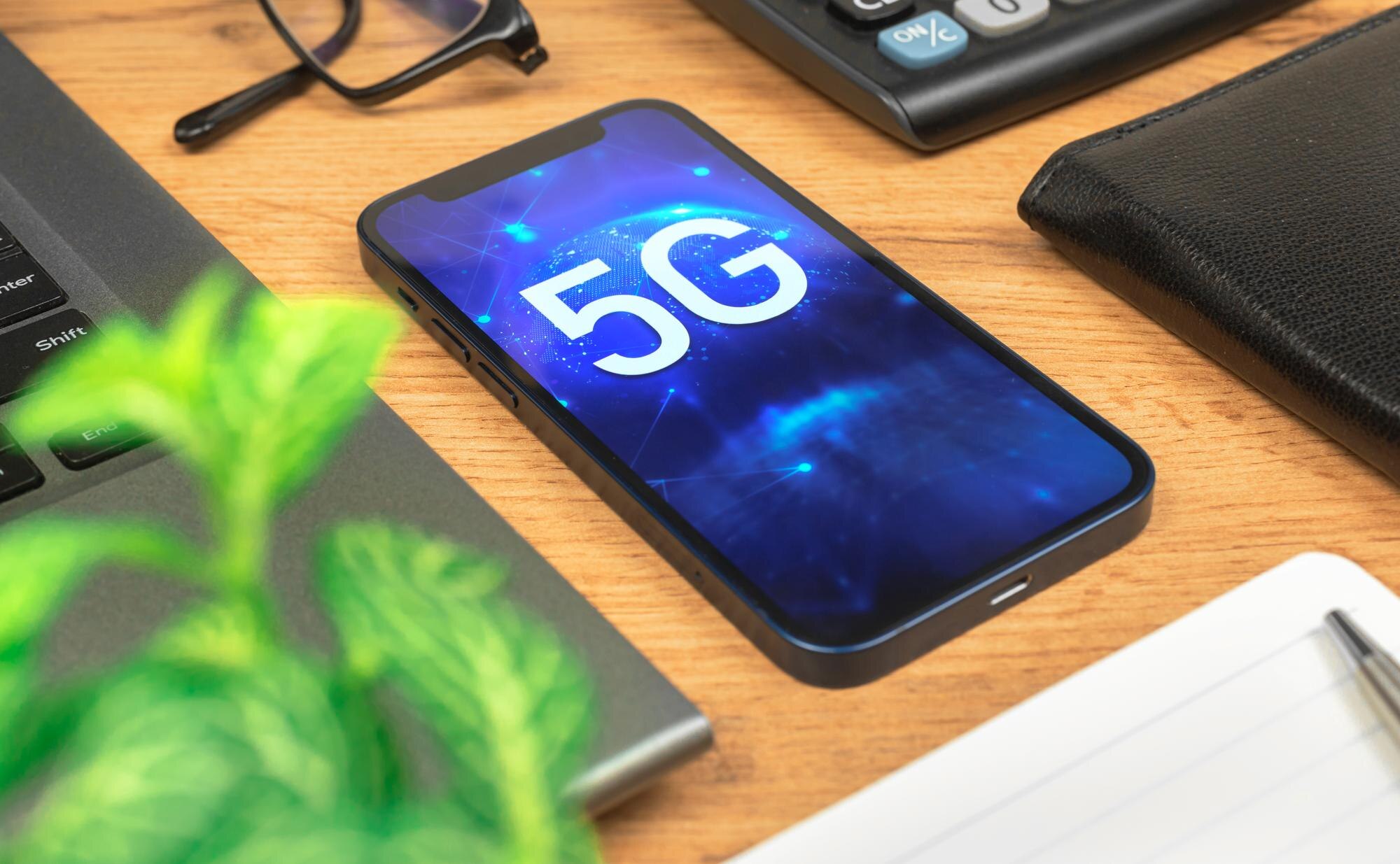 Telefon z siecią 5G, tło z hologramem. Pulpit biznesowy. Zdjęcie koncepcyjne szybkiego Internetu, nowej generacji sieci