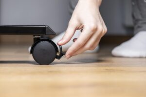 Person39s hand engaging the brake on a black caster wheel of modern furniture ensuring stability and safety for mobility in a contemporary home setting