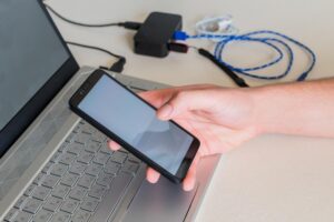 Męskie ręki sprawdza telefon komórkowego obok laptopa na biurku Selekcyjna ostrość