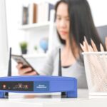 Bezprzewodowy router i kobieta używa smartphone w biurze