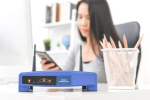 Bezprzewodowy router i kobieta używa smartphone w biurze